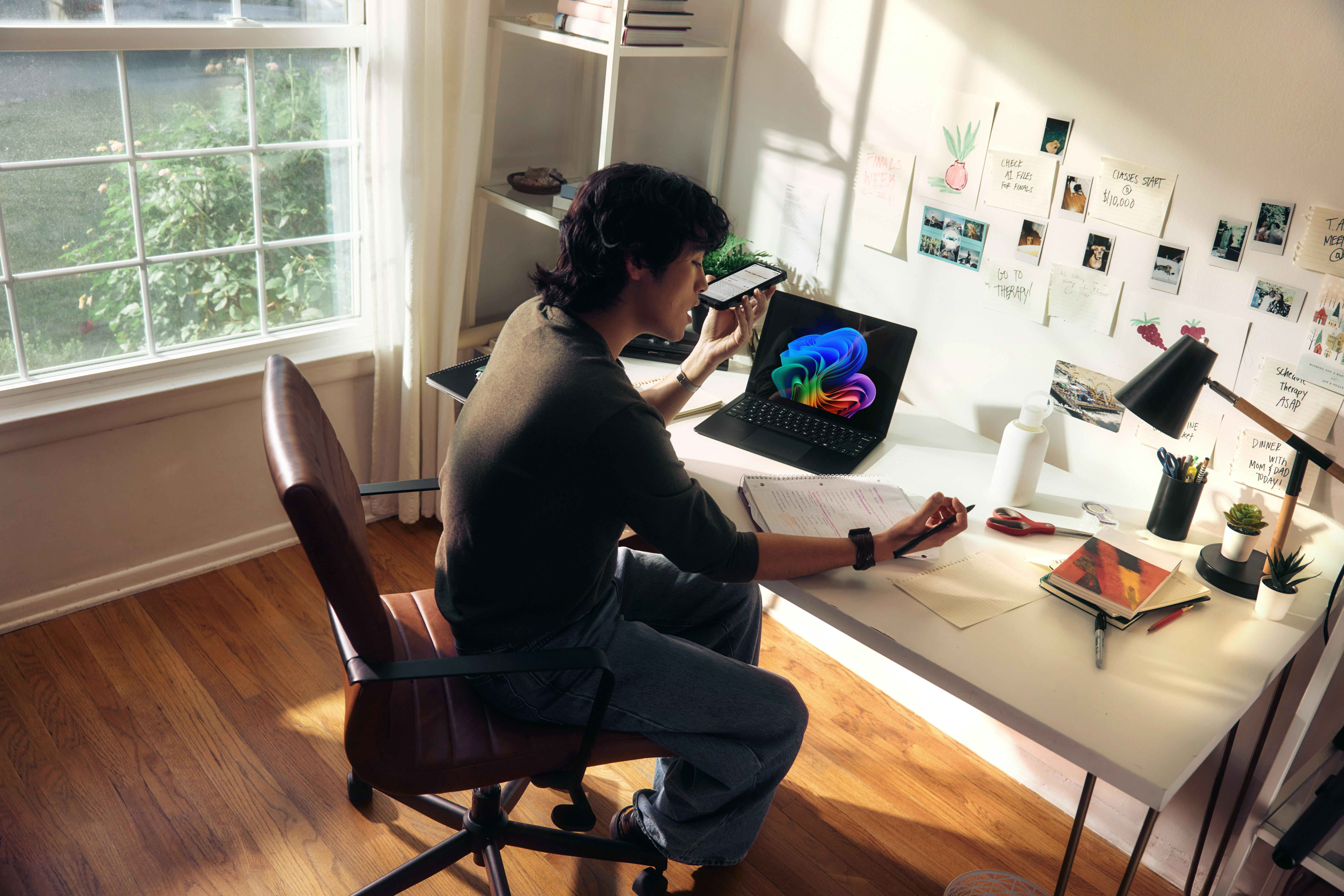 Image of a man sitting infront of a laptop talking on the phone